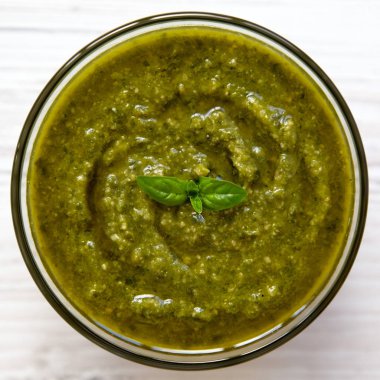 Beyaz ahşap arka planda, üstten görünüm taze yapılmış fesleğen pesto kase. Yakın çekim.