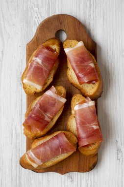 Crostini ile serrano jambonu beyaz tahta masada rustik ahşap tahta üzerinde üst görünüm. Düz, tepegöz, yukarıdan yatıyordu. Portre.