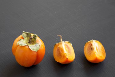 Siyah yüzey, yan görünüm taze Trabzon hurması. Yakın çekim. Kopya alanı.