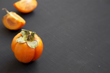 Siyah arka planda, yan görünüm taze Trabzon hurması. Metin için yer.