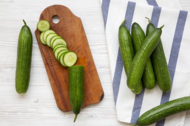 Taze çiğ yeşil salatalık, üstten görünüm. Yukarıdan, ek yük düz yatıyordu. Beyaz ahşap zemin.