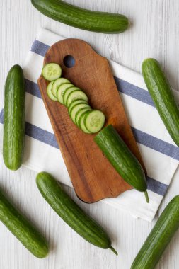 Taze çiğ yeşil salatalık, havai görünümü. Yukarıdan, üstten görünüm düz yatıyordu. Beyaz ahşap yüzey.