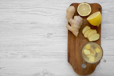 Beyaz ahşap arka plan, üstten görünüm üzerinde ahşap tahta üzerinde limon ile ev yapımı zencefil çayı fincan. Kopya alanı.