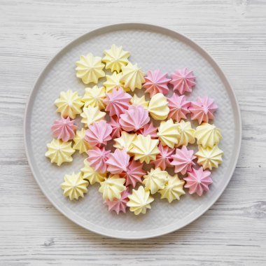 Mini meringues Beyaz ahşap arka plan, havai görünümü üzerinde gri plaka üzerinde. Yukarıdan, üstten görünüm düz yatıyordu. Yakın çekim.