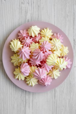 Mini meringues pembe plaka yüzeyinde bir beyaz tahta, havai görünümü üzerinde. Yakın çekim. 