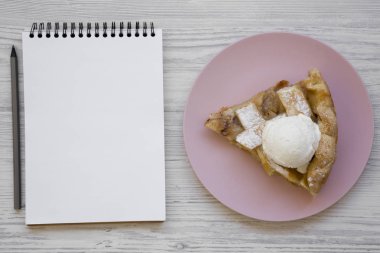 Ev-pişmiş elma pasta dondurma pembe plaka ile dilim. Boş not defteri. Metin için yer. Düz, tepegöz, yukarıdan yatıyordu.