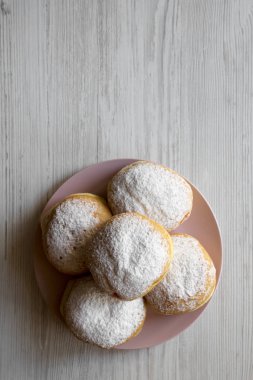Üstten görünüm, Beyaz ahşap masa üzerinde pembe plaka üzerinde pudra şekeri ile ev yapımı lezzetli çörekler. Düz, tepegöz, yukarıdan yatıyordu. Kopya alanı.