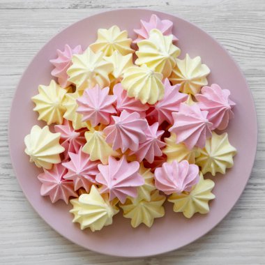 Mini meringues Beyaz ahşap zemin, üstten görünüm üzerinde pembe plaka üzerinde. Düz, tepegöz, yukarıdan yatıyordu.