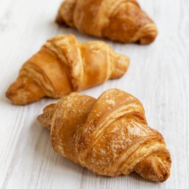 Taze kruvasanlar yan görünüm beyaz tahta masada. Seçici odak. 