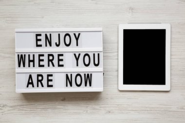 'Şimdi neredesin zevk' kelime lightbox, tablet ile beyaz ahşap arka plan, havai görünümü üzerinde boş perde üstünde. Üstten görünüm, düz yatıyordu, yukarıdan.