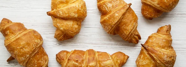 stock image Freshly baked golden croissants on white wooden background, top view. From above, overhead, flat lay.