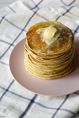 Pembe plaka, yan görünüm üzerinde tereyağı ile ev yapımı krep yığını. Portre.