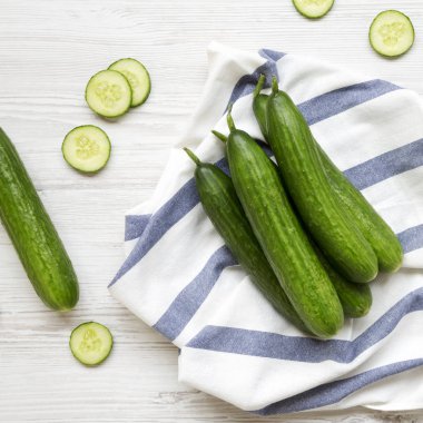 Beyaz ahşap yüzey, en iyi görünümü üzerinde taze çiğ yeşil salatalık. Yukarıdan, ek yük düz lay. 