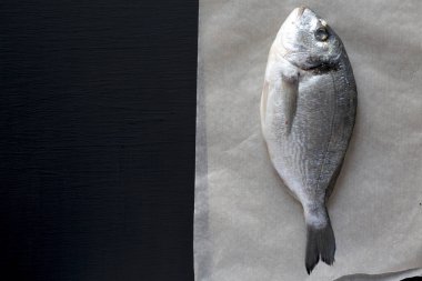 Taze dorado balığı koyu arka plan üzerinde üstten görünüm kagit üzerinde. Yukarıdan, ek yük düz yatıyordu. Kopya alanı.