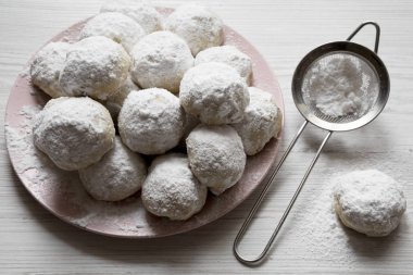 Ev yapımı beyaz Meksika düğün çerezler üzerinde pembe plaka üzerinde beyaz ahşap yüzey, yakın çekim.