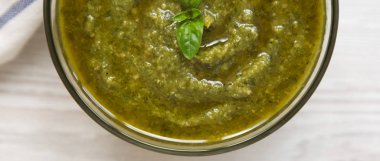 Beyaz ahşap yüzey, en iyi görünüm taze yapılmış fesleğen pesto kase. Yakın çekim.