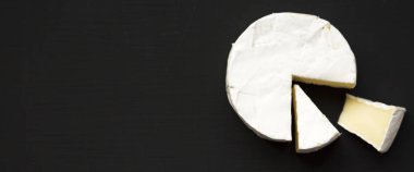 Peynir camembert veya koyu siyah arka plan üzerine brie. Süt üretimi. Havai görünümü. Yukarıdan Lay, düz. Metin için yer.