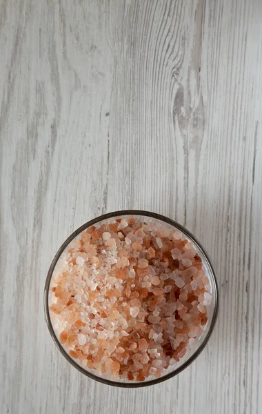 Himalayan sea salt in a glass bowl on white wooden table, top view. Flat lay, overhead, from above. Space for text.