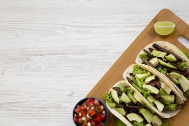 Mısır ekmeği ızgara sığır eti, avokado, kireç ve bambu gemide salsa ile yukarıdan görüntüleyin. Düz yatıyordu, en iyi görünüm. Metin için yer.