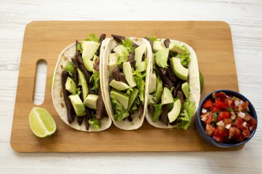 Mısır ekmeği ızgara sığır eti, avokado, kireç ve Bambu tahta, yan görünüm üzerinde salsa ile. 