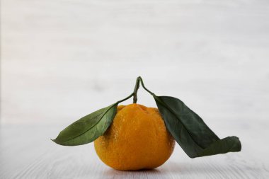 Beyaz ahşap arka plan, yan görünüm üzerinde taze olgun soyulmamış mandalina. Yakın çekim.