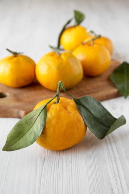 Beyaz ahşap yüzey, yan görünüm üzerinde taze olgun sulu mandalina. Seçici odak. Portre.