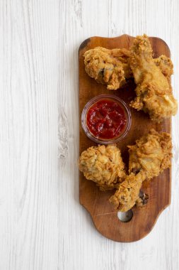 Beyaz ahşap arka plan, üstten görünüm üzerinde ahşap tahta üzerinde soslu kızarmış tavuk sopaları. Tepegöz, lay, yukarıdan düz. Kopya alanı.