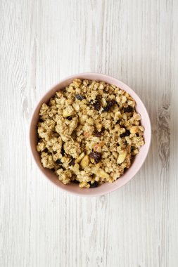 Beyaz ahşap arka plan, havai görünümü üzerinde pembe kase meyve granola. Yukarıdan, üstten görünüm düz lay.