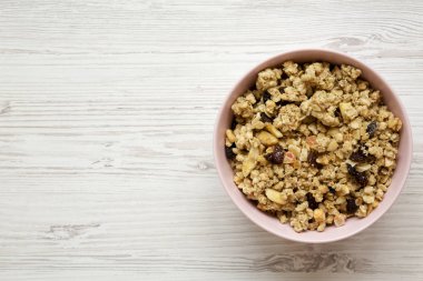 Beyaz ahşap yüzey, en iyi görünümü üzerinde pembe kase meyve granola. Yukarıdan, ek yük düz lay.
