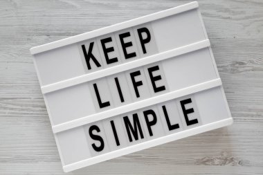 'Hayat basit tutmak' kelimeleri modern beyaz ahşap masa, havai görünümü üzerinde kurulu. Yukarıdaki üzerinden düz lay. 