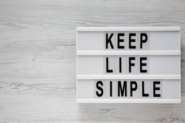 'Hayat basit tutmak' kelimeleri modern beyaz ahşap zemin, havai görünümü üzerinde kurulu. Yukarıdan Lay, düz. Kopya alanı.