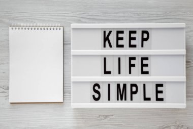 'Hayat basit tutmak' kelime modern yönetim kurulu, Beyaz ahşap yüzey, havai görünümü üzerinde boş not etmek üstünde. Yukarıdan Lay, düz. Metin için yer.