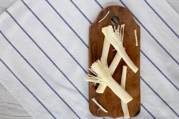 String cheese on rustic wooden board, top view. Healthy snack. Flat lay, overhead, from above. Copy space.