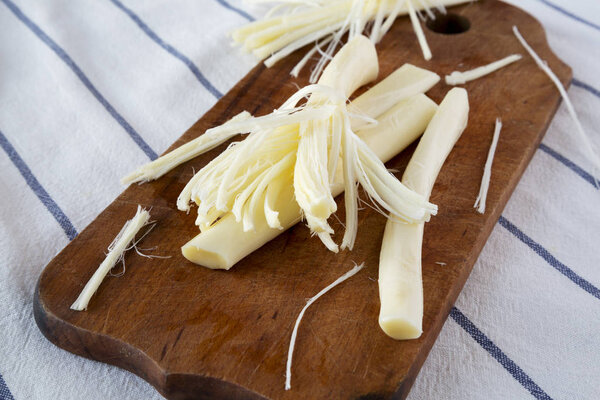 String cheese on rustic wooden board on striped napkin, side view. Healthy snack. Closeup.