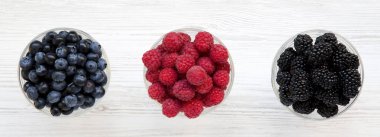 Meyveleri içeren kase: yaban mersini, böğürtlen, ahududu, havai görünümü. Sağlıklı beslenme. Yukarıdan, üstten görünüm, düz yatıyordu.