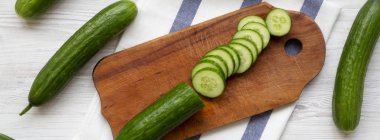 Taze çiğ yeşil salatalık, üstten görünüm. Yukarıdan, ek yük düz yatıyordu. Beyaz ahşap zemin.