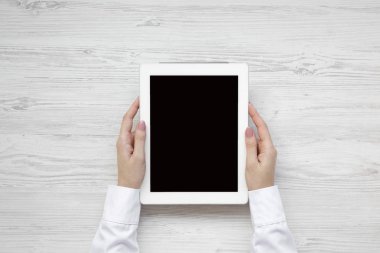 Tablet bir beyaz ahşap zemin, havai görünümü kullanarak eller. Yukarıdan, üstten görünüm, düz yatıyordu.