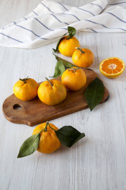 Beyaz ahşap arka plan, yan görünüm üzerinde taze olgun sulu mandalina. Portre.