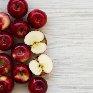 Beyaz ahşap arka plan, havai görünümü üzerinde çiğ kırmızı elma. Yukarıdan, üstten görünüm düz yatıyordu. Kopya alanı.