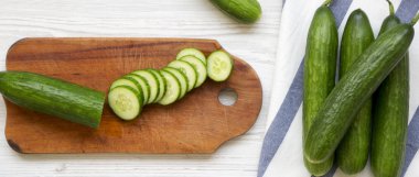 Taze çiğ yeşil salatalık, üstten görünüm. Yukarıdan, ek yük düz yatıyordu. Beyaz ahşap yüzey.