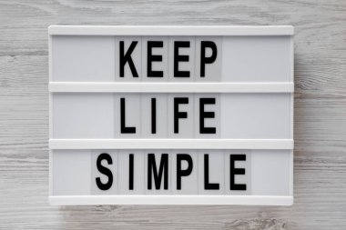 'Hayat basit tutmak' kelimeleri modern beyaz ahşap zemin, üstten görünüm üzerinde kurulu. Yukarıdaki üzerinden düz lay. 