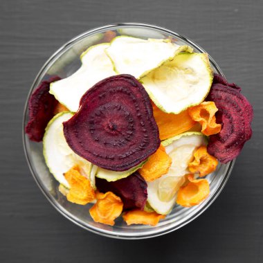 Sebze cips siyah yüzey, havai görünümü üzerinde tam kase. Üstten görünüm, düz yatıyordu. 