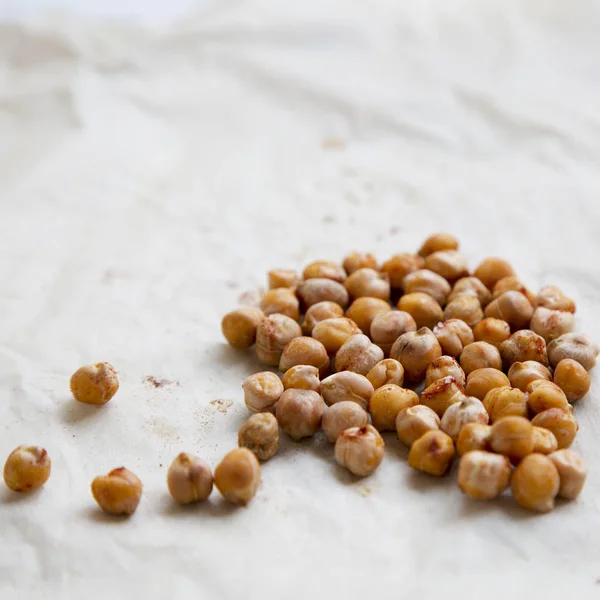 Roasted chickpeas with spices on baking paper, close-up.