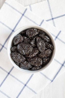 Beyaz ahşap zemin, havai görünümü üzerinde kuru kuru erik tam kase. Yukarıdan, üstten görünüm düz lay.