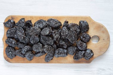 Beyaz ahşap bir masa havai görünümü üzerinde rustik ahşap tahta üzerinde kuru erik. Yakın çekim. Yukarıdan, üstten görünüm düz lay.