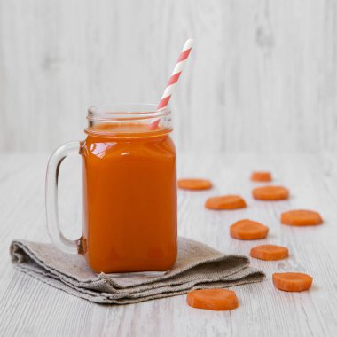 Cam sürahi havuç güler yüzlü beyaz ahşap arka planda, yan görünüm. 