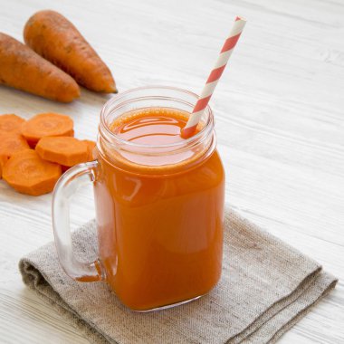 Cam sürahi havuç güler yüzlü beyaz ahşap zemin üzerinde yakın çekim. Yan görünüm.