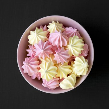 Bir pembe mini meringues siyah yüzey, en iyi görünümü üzerinde top. Yukarıdan, düz, ek yükü yatıyordu. Portre.