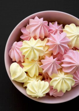 Bir pembe mini meringues siyah yüzey, en iyi görünümü üzerinde top. Yukarıda, ek yükü. Portre.