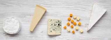 Çeşitli peynirler Beyaz ahşap arka planda, üstten görünüm. Düz, tepegöz, yukarıdan yatıyordu.